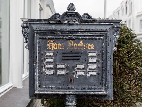 Alte gusseiserne Klingeltafel mit beschrifteten Namensschildern vor einem Haus auf Norderney