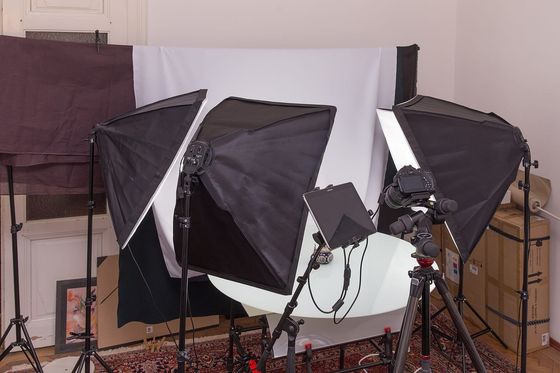 Kleines Fotostudio mit drei Softboxen, Kamera auf Stativ und weißem Hintergrund