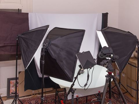 Kleines Fotostudio mit drei Softboxen, Kamera auf Stativ und weißem Hintergrund